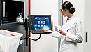 Low-angle rear view of an experienced female pharmacist using a computer while managing the drug stock in a contemporary pharmacy with modern technology
