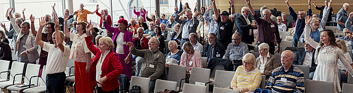 Blick in eine Konferenzhalle, das Publikum macht bei Fitness-Übungen mit
