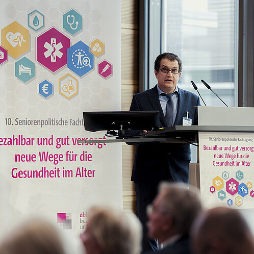 Ein Mann steht hinter einem Rednerpult und spricht in das Mikrofon