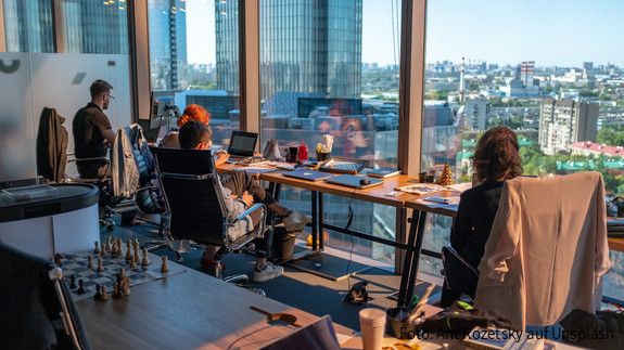 Menschen an einem modernen Arbeitsplatz vor Laptops