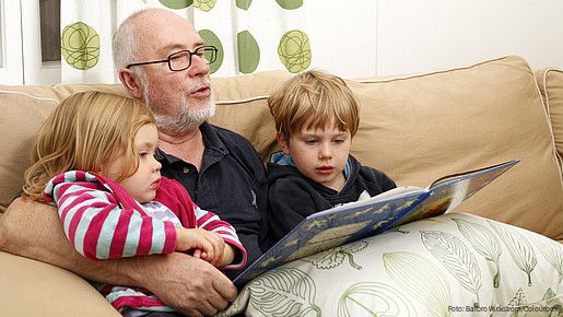 people, person, scandinavian, adult, child, male, man, senior, grandfather, grandparent, girl, boy, grandchild, group, age, 60, 3, 5, sitting, sofa, inside, indoors, livingroom, home, daylight, family, generation, togetherness, love, harmony, loving, reading, book, story, telling, enjoying, feeling, tenderness, happiness, happy, joyful, joy, entertainment, entertaining, blond, grey, casual, relaxed, relaxing, lifestyle, wellness