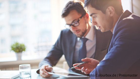Digitalisierung Zwei Männer im Büro sehen gemeinsam auf Tablet und besprechen sich