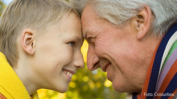 Tag der sozialen Gerechtigkeit Großvater und Enkelsohn lehnen die Köpfe aneinander und lächeln sich gegenseitig an.