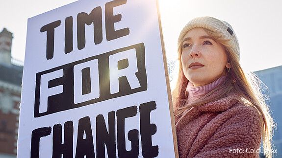 Weltfrauentag dbb jugend Eine junge Frau hält bei einer Demonstration ein Plakat mit der Aufschrift "Time for Change" hoch.
