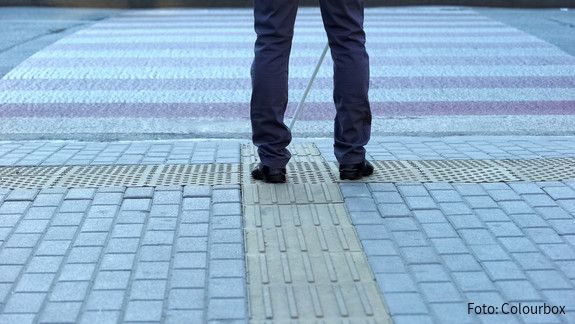 Beine von Hinten am Straßenrand mit einem Blindenstock