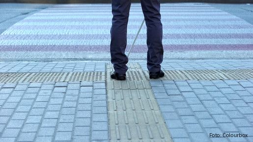 Beine von Hinten am Straßenrand mit einem Blindenstock