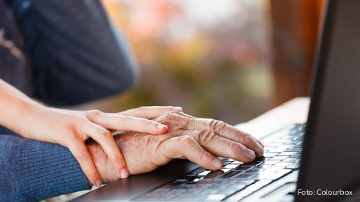 Die Hand einer älteren Person liegt auf dem Mauspad eines Laptops. Auf der Hand liegt die eine jüngeren Person.