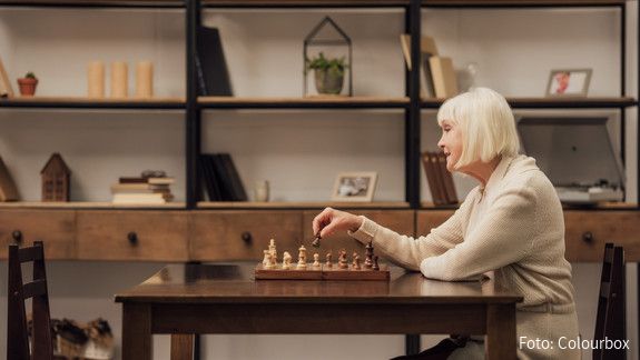 selective focus of senior woman sitting at table and playing chess in living room