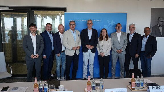 Eine Gruppe formal gekleideter Menschen steht in einem Konferenzraum um luxemburgischen Innenministerium.