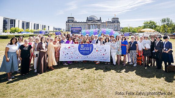Gruppenfoto von Menschen in formaler Kleidung vor dem Bundestag