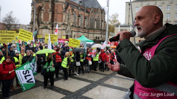 Volker Geyer spricht auf einer Bühne vor den Protestierenden