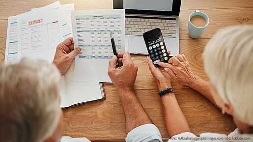 Home budget, finance planning and senior couple calculating their expenses, bills or income during retirement with a calculator, laptop and paper documents from behind. Man and woman discuss savings.
