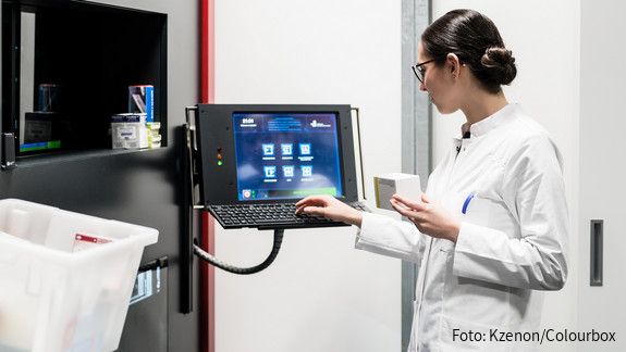Low-angle rear view of an experienced female pharmacist using a computer while managing the drug stock in a contemporary pharmacy with modern technology