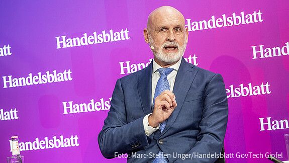 Ein Mann sitzt auf einer Bühne und spricht.