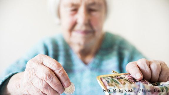 Eine unglücklich wirkende Seniorin zählt am Tisch die wenigen Münzen ihre Pension.