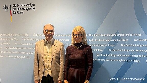 Die Pflegebevollmächtigte der Bundesregierung, Katrin Staffler, und der Vorsitzende der dbb bundesseniorenvertretung, Horst Günther Klitzing, stehen vor einer blauen Pressewand der Bevollmächtigten der Bundesregierung für Pflege. Beide sind der Kamera zugewandt. Im Hintergrund sind das Bundesadler-Logo sowie mehrfach der Schriftzug „Die Bevollmächtigte der Bundesregierung für Pflege“ zu sehen.