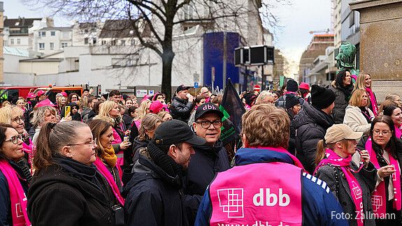 Eine Gruppe Menschen in pinken Warnwesten demonstriert auf einem öffentlichen Platz